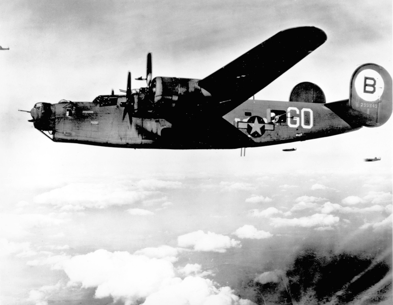 Black & white photograph of a B-24 in flight, with two other planes in distance