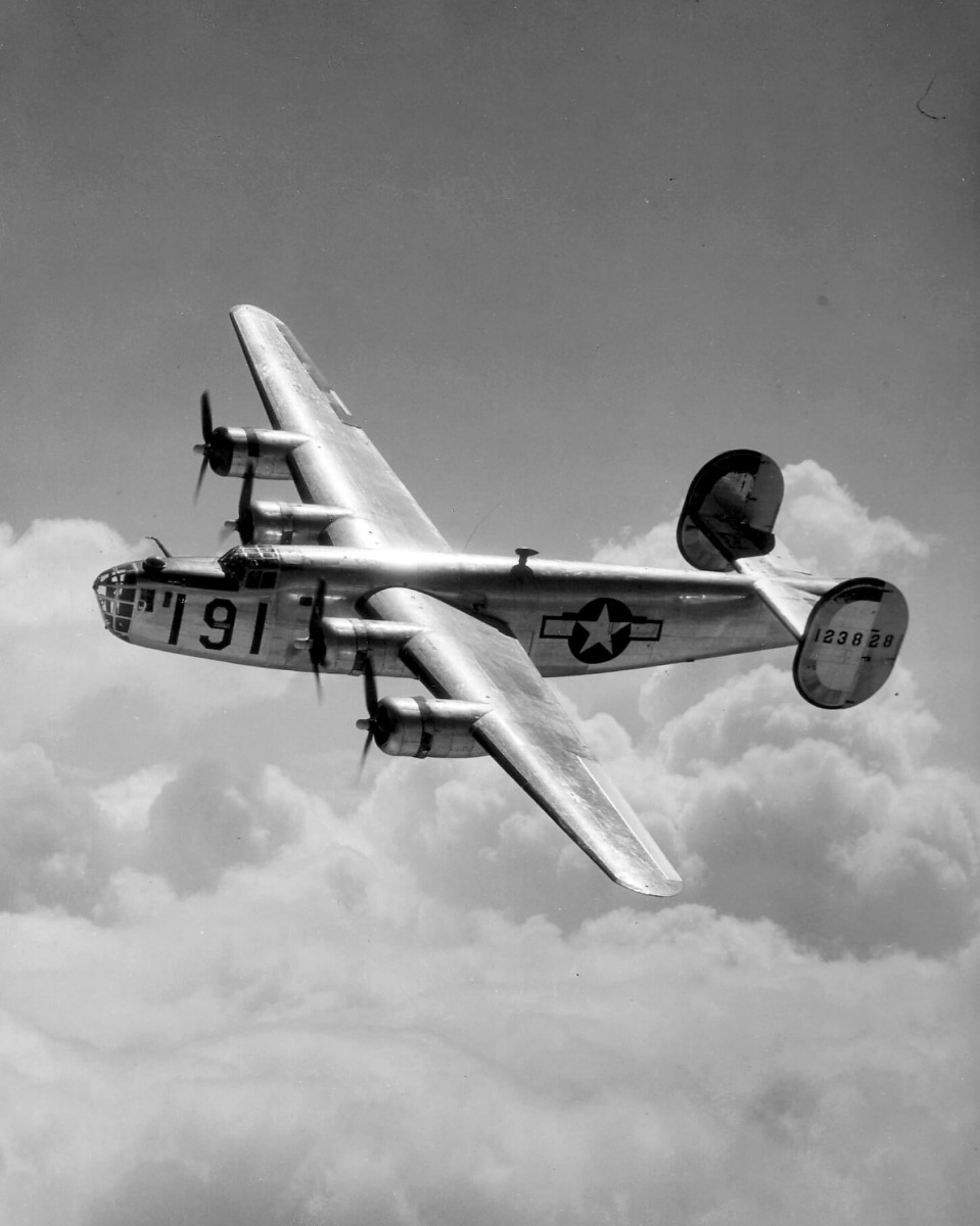 Black & white photograph of a B-24 liberator in flight, taken from the air